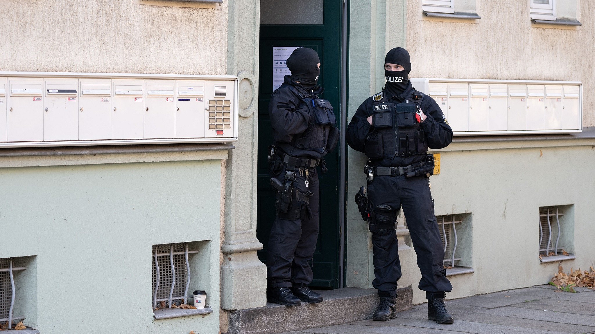 Polizisten stehen während einer Razzia gegen mutmaßliche Rechtsextreme in einem Hauseingang im Dresdner Stadtteil Cotta.