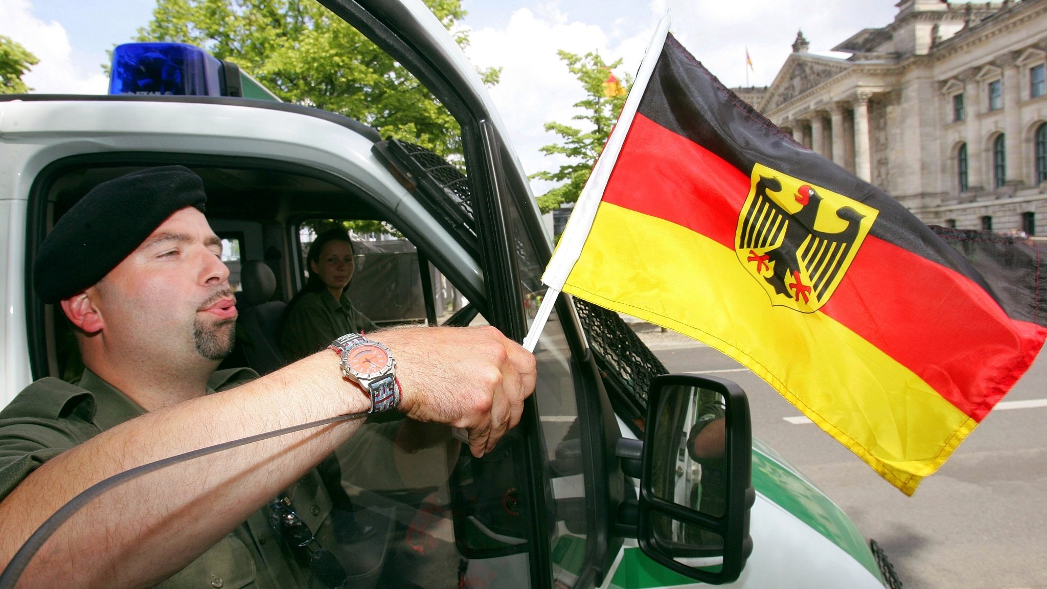 Polizist befestigt eine Deutschlandfahne an seinem Polizeiwagen vor dem Reichstagsgebäude