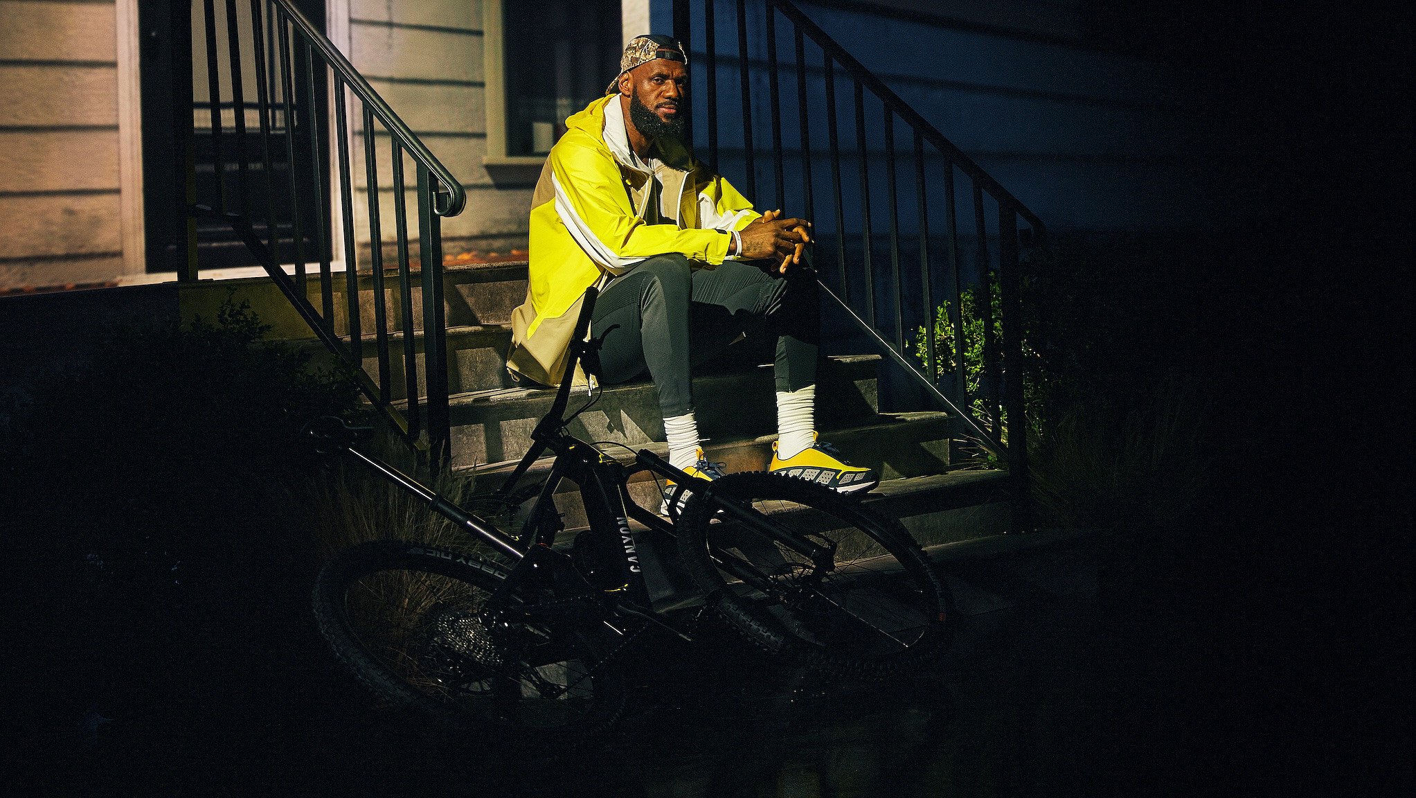 LeBron James sitzt mit Fahrrad vor einem beleuchteten Hauseingang